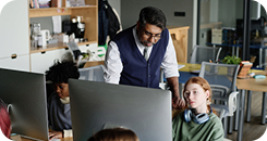 Educador da Amplia Plataforma de Ensino orientando alunos durante atividade em laboratório de informática.