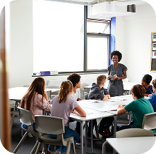 Professora liderando discussão com grupo de alunos, incentivando aprendizado colaborativo com apoio da Amplia Plataforma de Ensino.